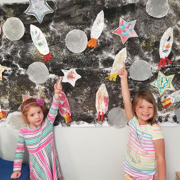 kids pointing at drawings of space ships